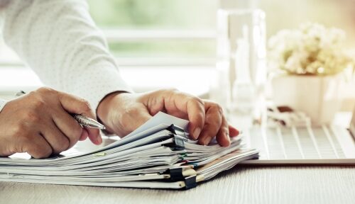 An expert combs through files on a desk as part of a case review.